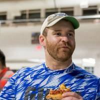 An alumnus eating pizza at the Fowling Fun Event